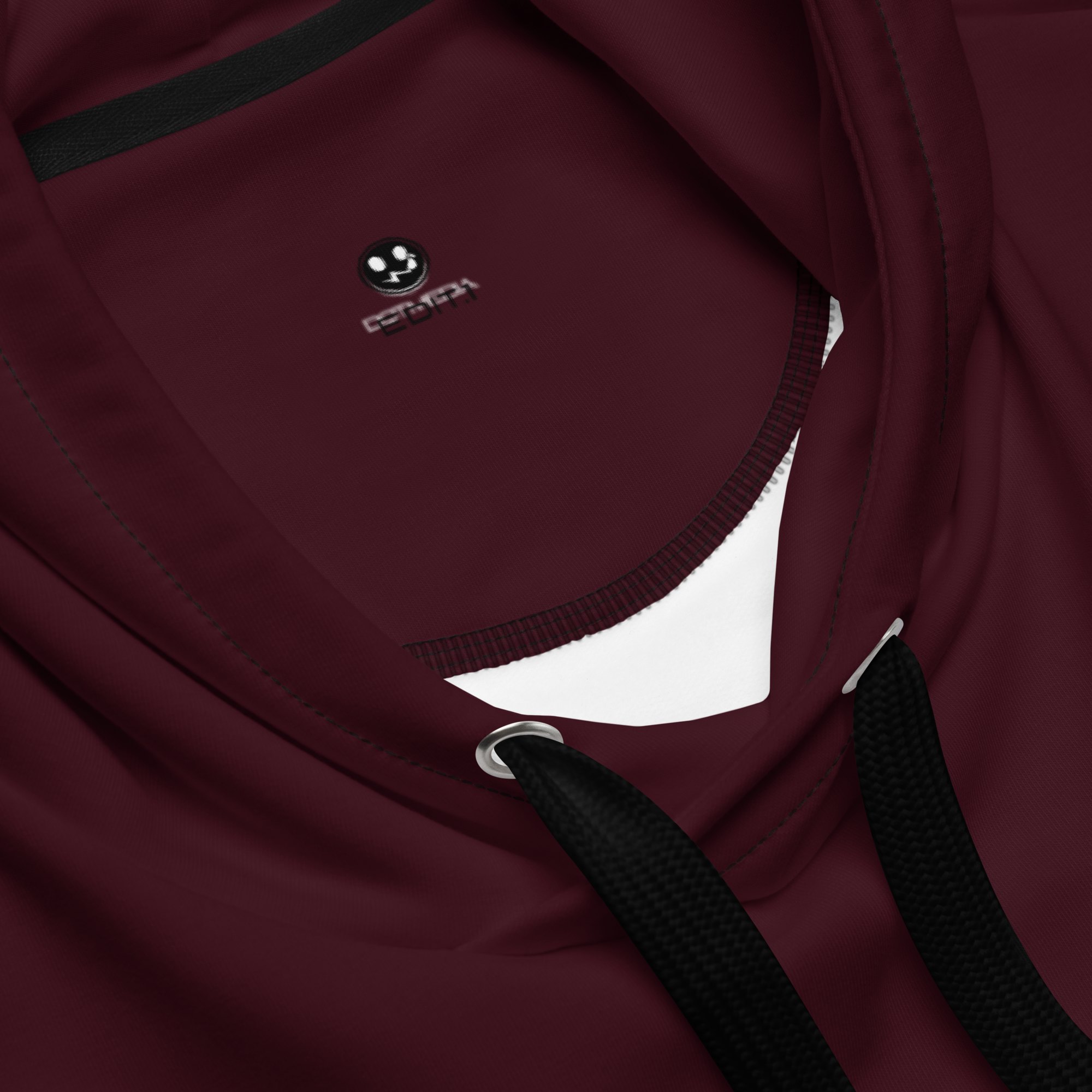 A close-up view of a burgundy hoodie showcases its soft, cosy fabric, highlighting the intricate stitching and design details. The hoodie features a prominent brand logo elegantly embroidered on the chest pocket, adding a stylish touch to the overall look. The rich maroon colour exudes warmth and sophistication, making it a versatile piece for any wardrobe.